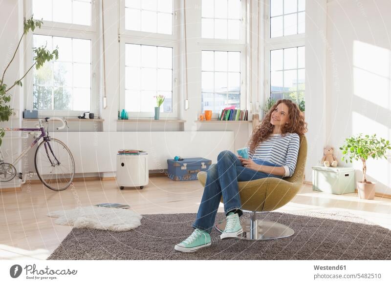 Relaxed woman at home sitting in chair smiling smile females women Seated armchair Arm Chairs armchairs Adults grown-ups grownups adult people persons
