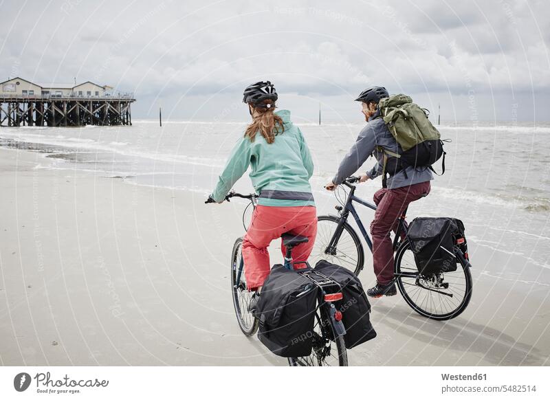 Germany, Schleswig-Holstein, St Peter-Ording, couple riding bicycle on the beach bikes bicycles twosomes partnership couples beaches transportation people