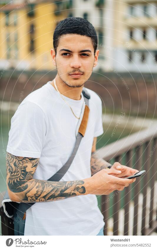 Young man outdoors holding cell phone Smartphone iPhone Smartphones men males mobile phone mobiles mobile phones Cellphone cell phones telephones communication