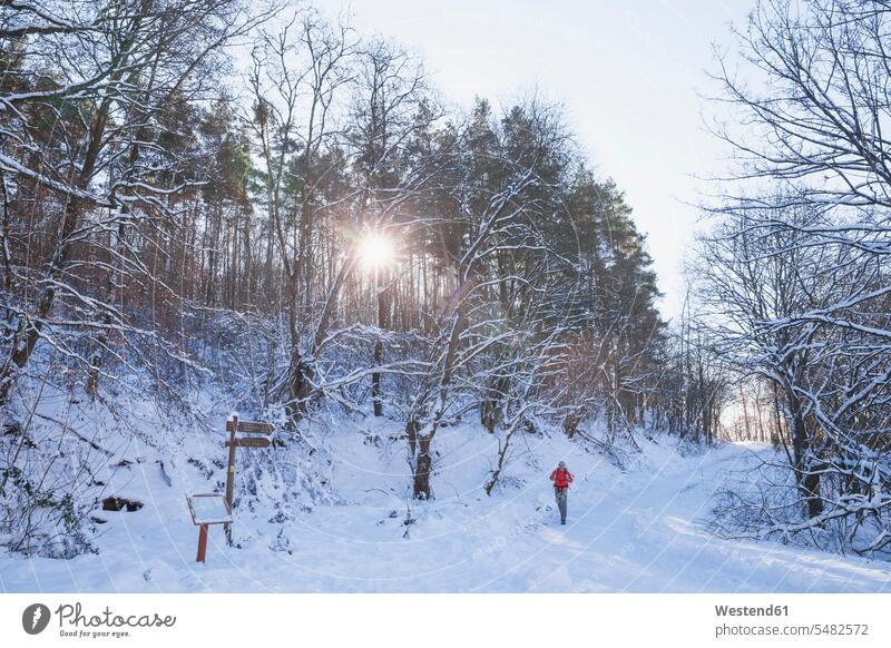 Germany, North Rhine-Westphalia, Eifel National Park, man hiking in snow-covered landscape evening mood casual leisure wear casual clothing casual wear