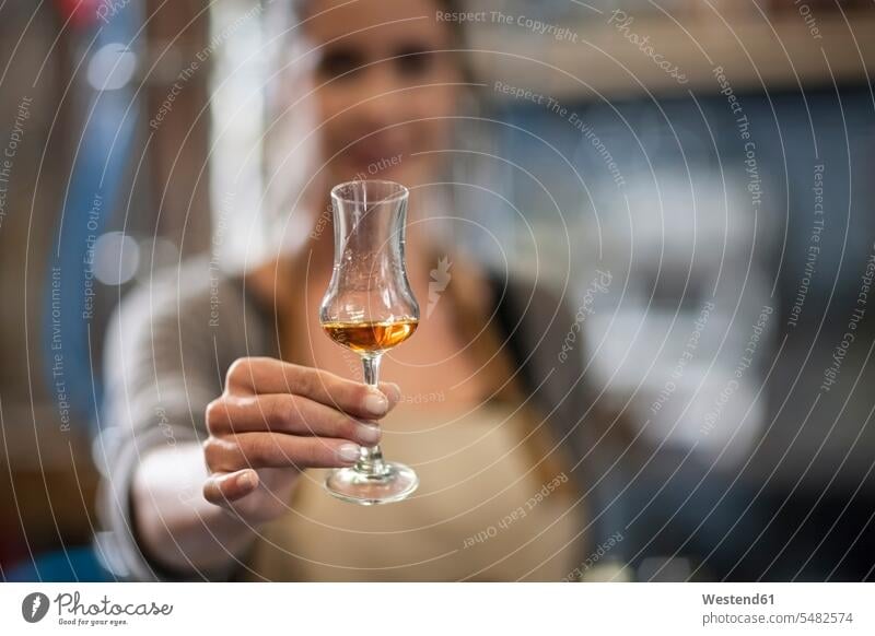 Woman holding liquor glass Glass Drinking Glasses distillery Distilleries shot glass shot glasses producing making caucasian caucasian ethnicity