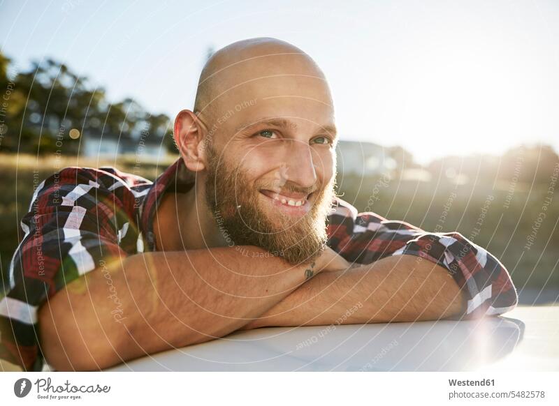 Portrait of bald young man with beard leaning on car roof men males portrait portraits Adults grown-ups grownups adult people persons human being humans