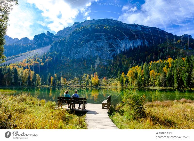 Germany, Bavaria, Upper Bavaria, Chiemgau, Inzell, Frillensee, hikers sitting on bench in autumn wooden bench Seated Travel couple twosomes partnership couples