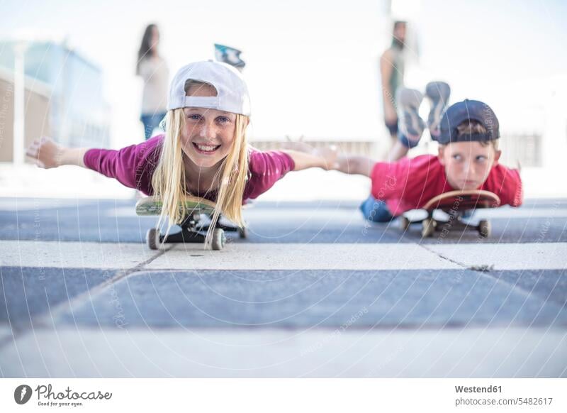 Kids skateboarding in the street, lying on belly Skate Board skateboards skateboarder skater skateboarders skaters laughing Laughter girl females girls boy boys