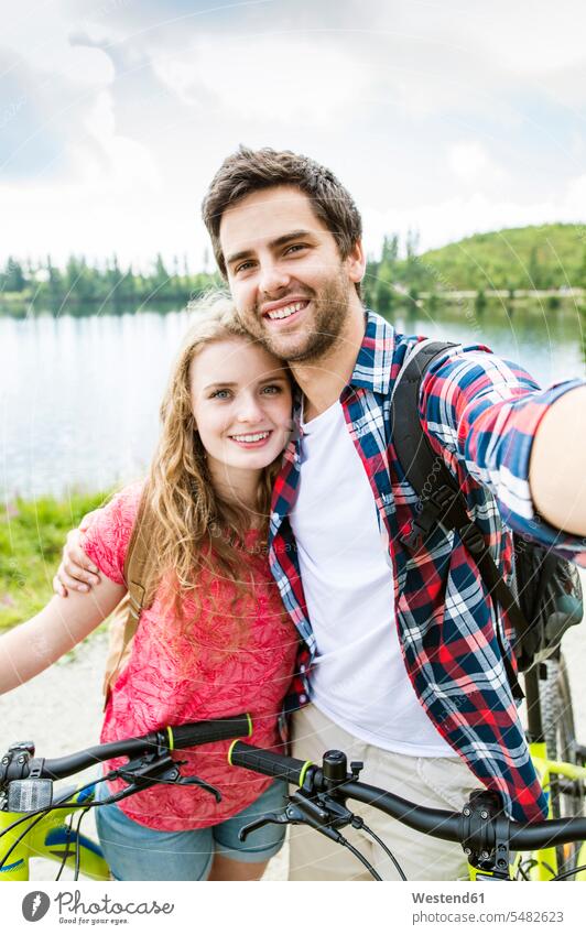 Young couple taking selfies on a bicycle trip excursion Getaway Trip Tours Trips Selfie Selfies happiness happy smiling smile cyclist photographing Bicycle tour