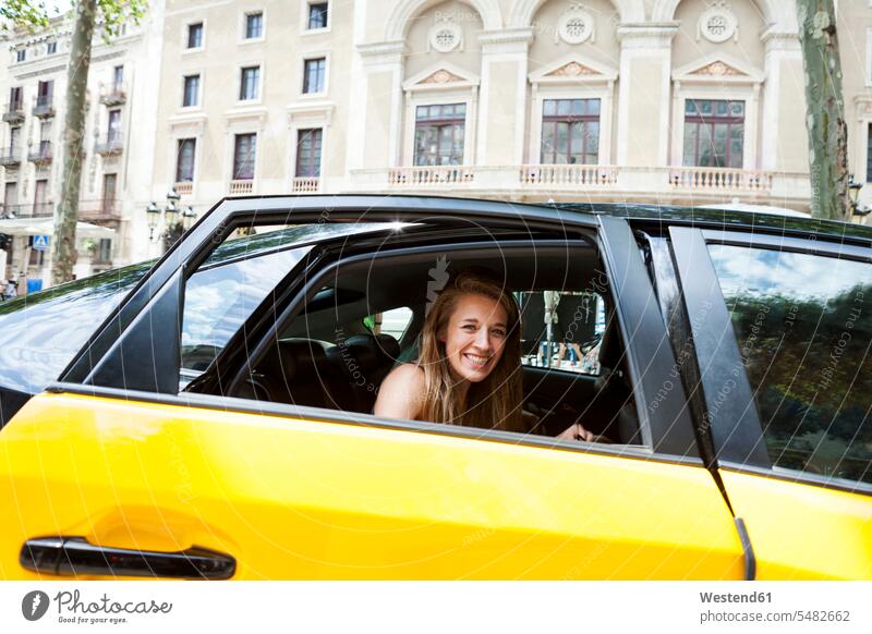 Spain, Barcelona, happy young woman looking out of taxi cab window Taxies females women car automobile Auto cars motorcars Automobiles motor vehicle