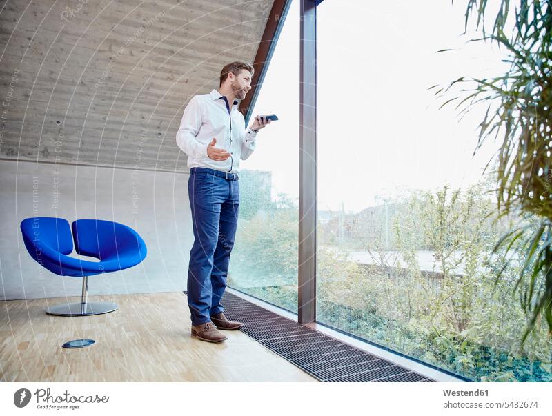 Businessman using cell phone in attic office at the window mobile phone mobiles mobile phones Cellphone cell phones on the phone call telephoning