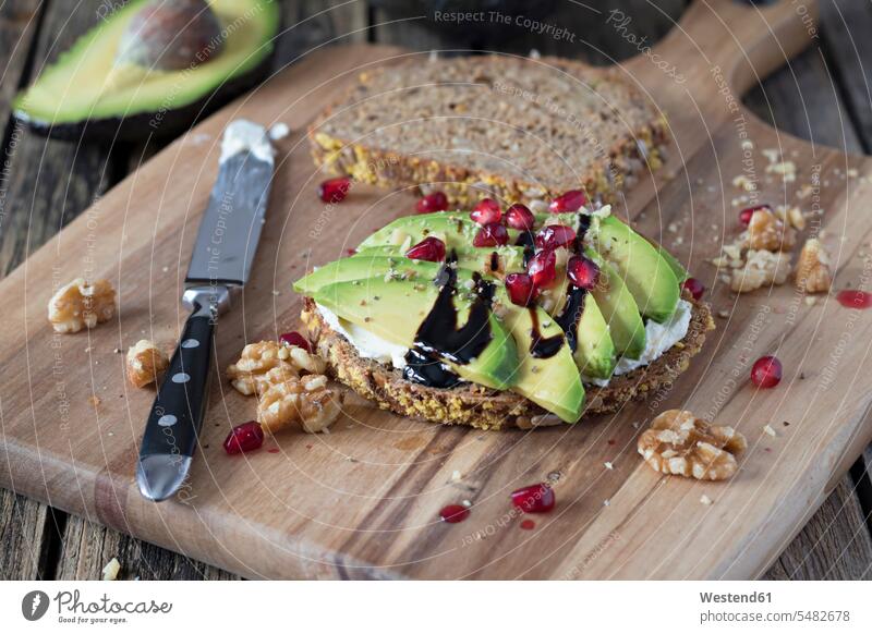 Protein bread slice with cream cheese, sliced avocado, walnuts and pomegranate seed on wooden board food and drink Nutrition Alimentation Food and Drinks Snack