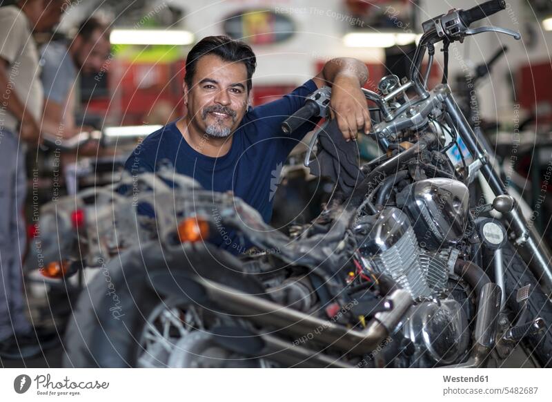 Portrait of smiling mechanic in motorcycle workshop motorbike Motor Cycle smile mechanician repairman mechanicians mechanists repairmen mechanics machinists