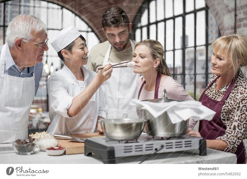Woman smelling ingredient in cooking class kitchen group of people Group groups of people female cook persons human being humans human beings chef cooks Chefs