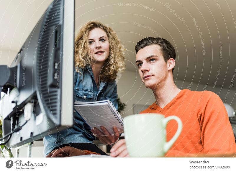 Two colleagues at desk looking at computer monitor eyeing business business world business life home office working from home home business At Work computers