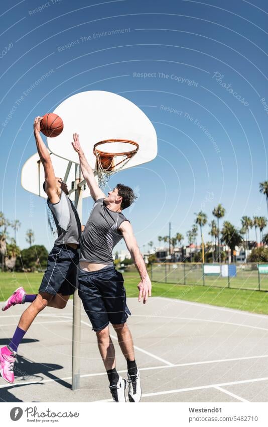 Two young men playing basketball on an outdoor court Recreational Pursuit Recreational Activities Recreational Pursuits Recreational Activity hobby hobbies
