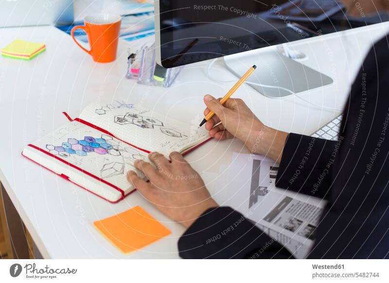 Woman drawing into notebook at desk in office notebooks desks sketching offices office room office rooms Table Tables workplace work place place of work