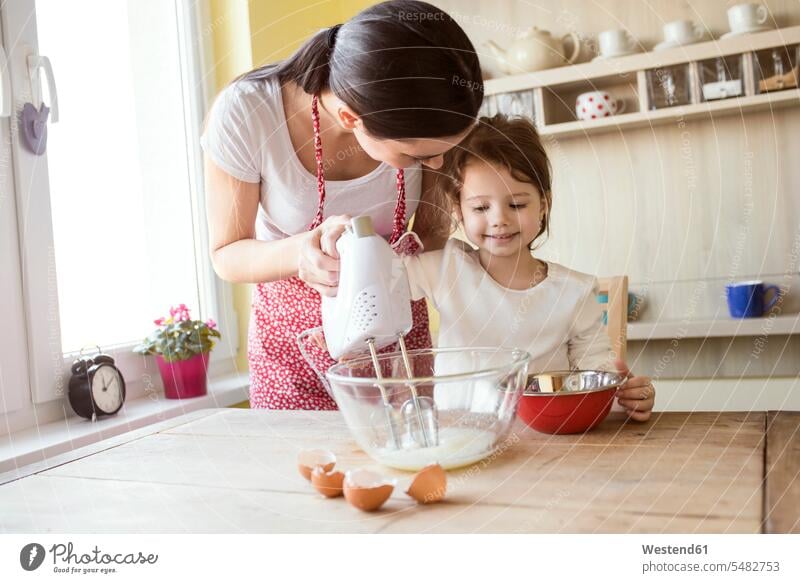 Portrait of smiling little girl and her mother baking together day daylight shot daylight shots day shots daytime happiness happy kitchen domestic kitchen