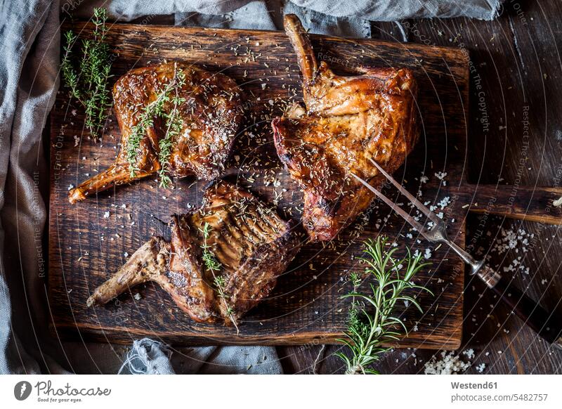 Baked rabbit legs on plate, thyme, rosemary and salt meat fork Thyme Thymus seasoned flavored spiced flavoured ready to eat ready-to-eat prepared rustic baked