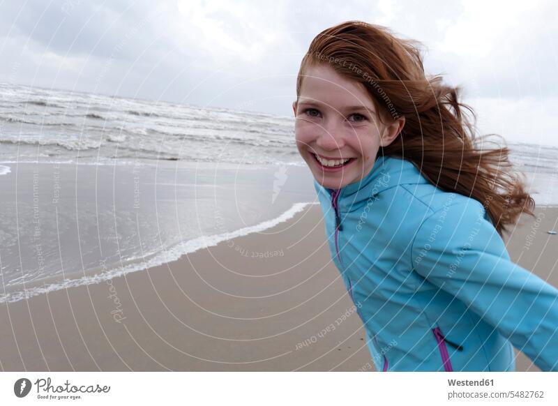 Portrait of smiling redheaded girl on a windy day on the beach one person 1 one person only only one person Windswept Windblown Windy cheerful gaiety Joyous