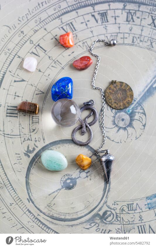 Semiprecious stones, pendulum, pendant and crystal ball on horoscope circle crystal balls glass sphere pendants western script snake serpentes serpents snakes