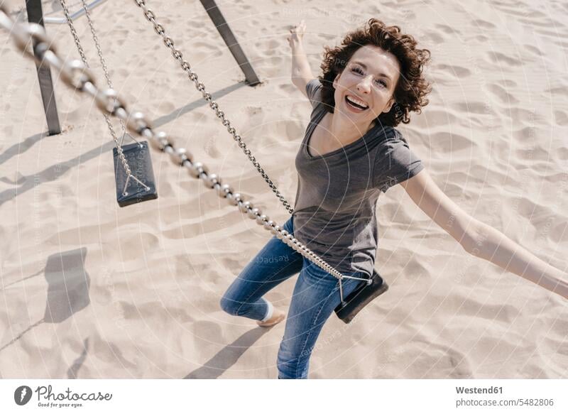 Happy woman on a swing swing set playground swing swingset laughing Laughter females women beach beaches positive Emotion Feeling Feelings Sentiments Emotions