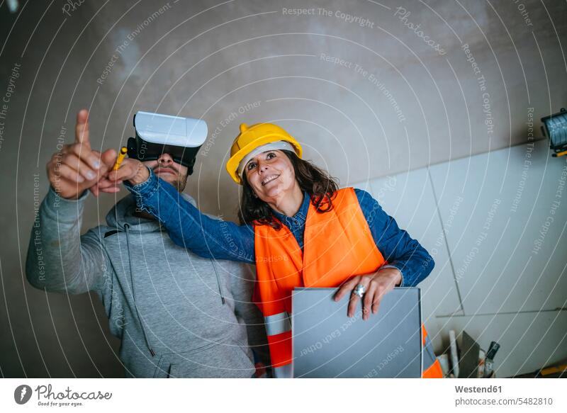 Woman on construction site showing a man with virtual reality glasses the house notepad pads Note Pad notepads Note Pads working At Work Building Site sites