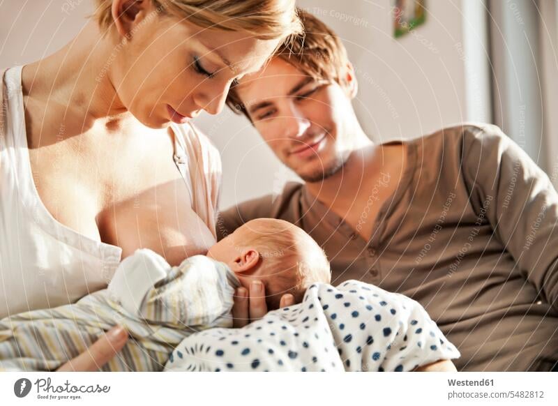 Mother breastfeeding her newborn baby with father watching mother mommy mothers ma mummy mama breast-feeding babies infants parents family families people