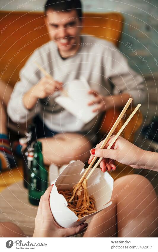 Young couple eating chinese take-away food at home box boxes toothy smile big smile open smile laughing chopstick chopsticks Unhealthy Eating unhealthy