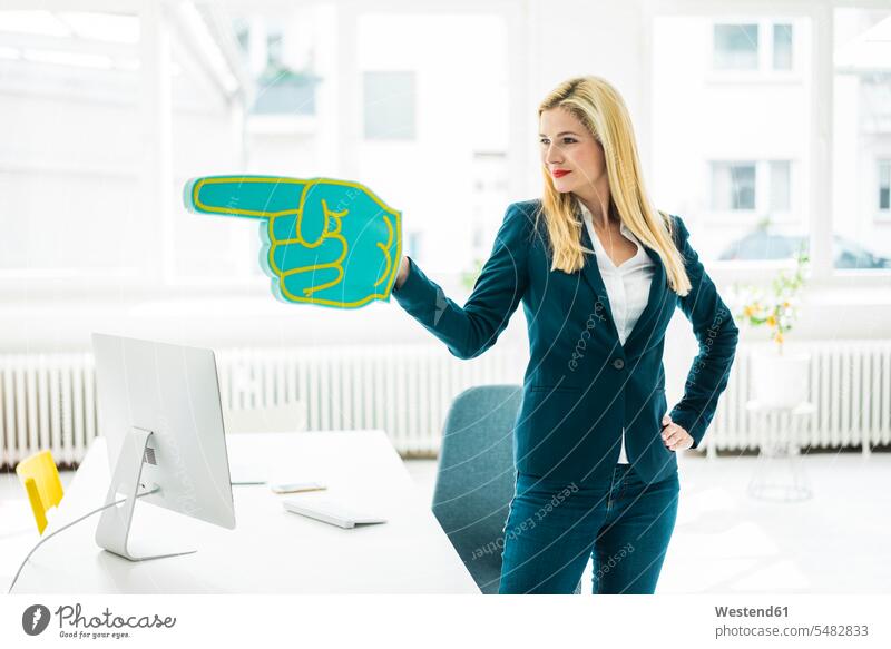 Confident businesswoman pointing with large hand in office Office Offices human hand hands human hands businesswomen business woman business women people
