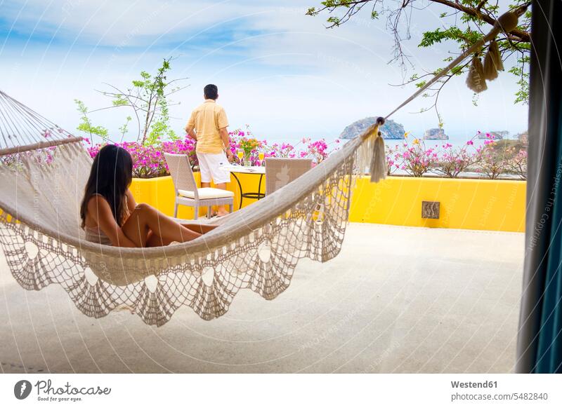 Man and young woman in hammock on terrace vacation holidays vacations tourism touristic relaxed relaxation Holidays hammocks Travel relaxing outdoors