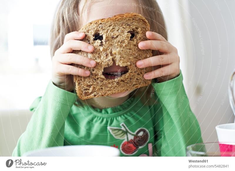 Little girl looking through holes in slice of bread Bread Breads child children kid kids Food foods food and drink Nutrition Alimentation Food and Drinks people
