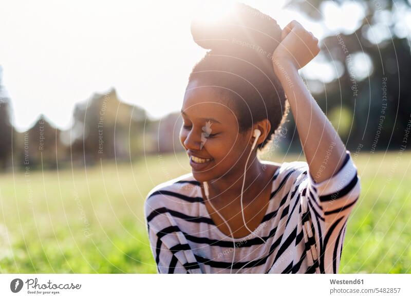 Smiling woman hearing music with earphones ear phone ear phones females women earbuds Earbud In-Ear Headphones ear bud Ear buds in-ear headphones headset Adults