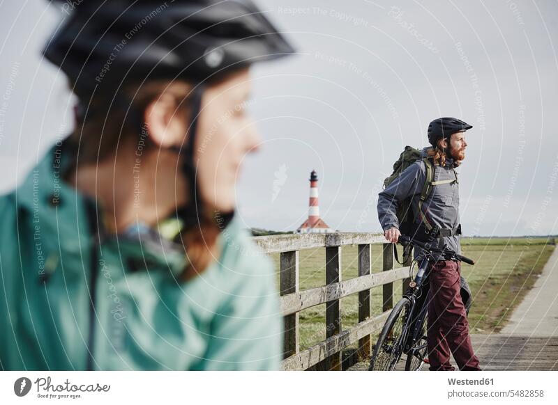 Germany, Schleswig-Holstein, Eiderstedt, couple on bicycle trip having a break near Westerheversand Lighthouse twosomes partnership couples bikes bicycles
