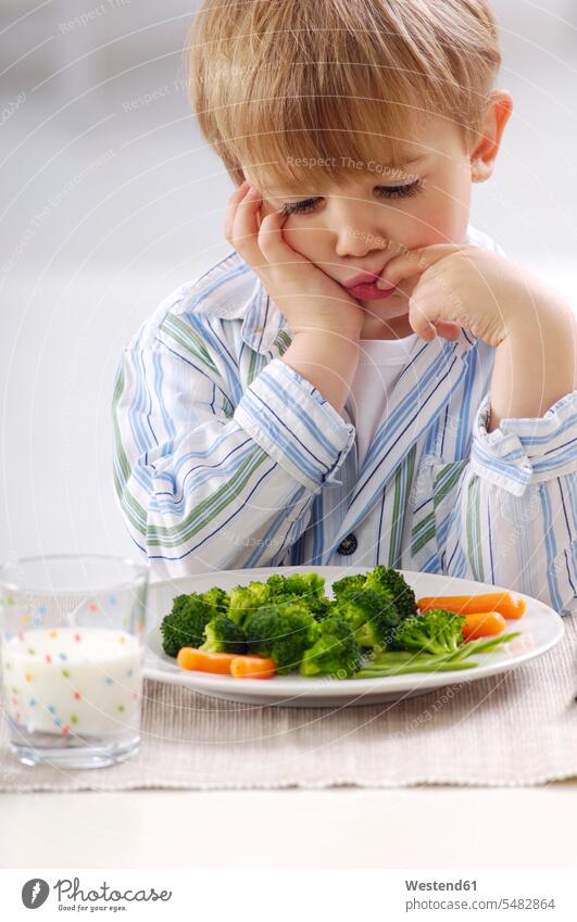 Portrait of little blond boy looking at plate with vegetables Glass Drinking Glasses casual leisure wear casual clothing casual wear casual clothes