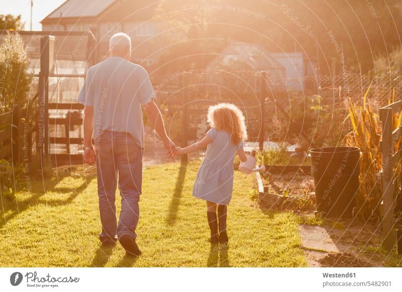 Little girl hand in hand with her uncle in the garden gardens domestic garden females girls child children kid kids people persons human being humans