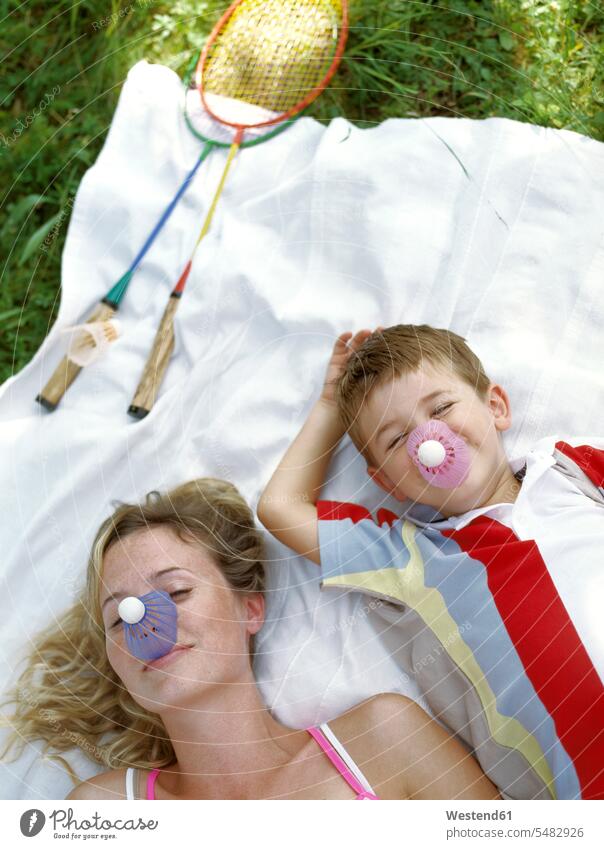Portrait of smiling mother and little son with shuttlecocks on their noses lying on blanket sons manchild manchildren mommy mothers mummy mama badminton sport