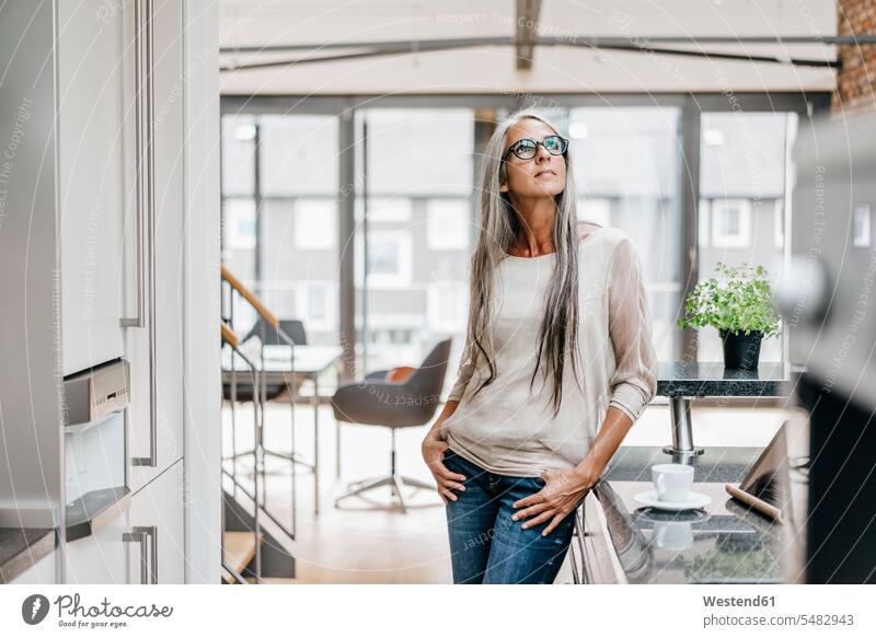 Woman with long grey hair in kitchen looking up woman females women Adults grown-ups grownups adult people persons human being humans human beings standing