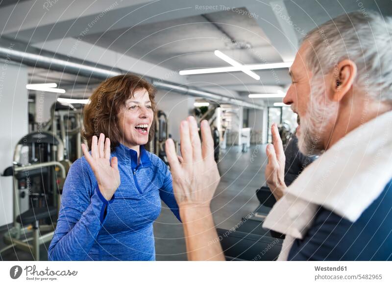 Happy senior man and woman high fiving after working out in gym gyms Health Club senior adults seniors old High Five Hi-Five high-fiving High-Five exercising