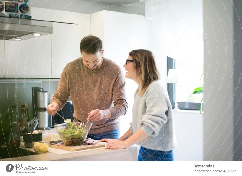 Happy couple preparing salad in kitchen together twosomes partnership couples Salad Salads happiness happy home at home people persons human being humans