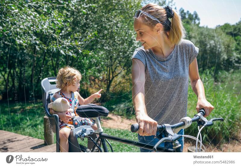 Mother taking a bike ride through the countryside with her daughter in a child seat mother mommy mothers ma mummy mama daughters bicycle bikes bicycles