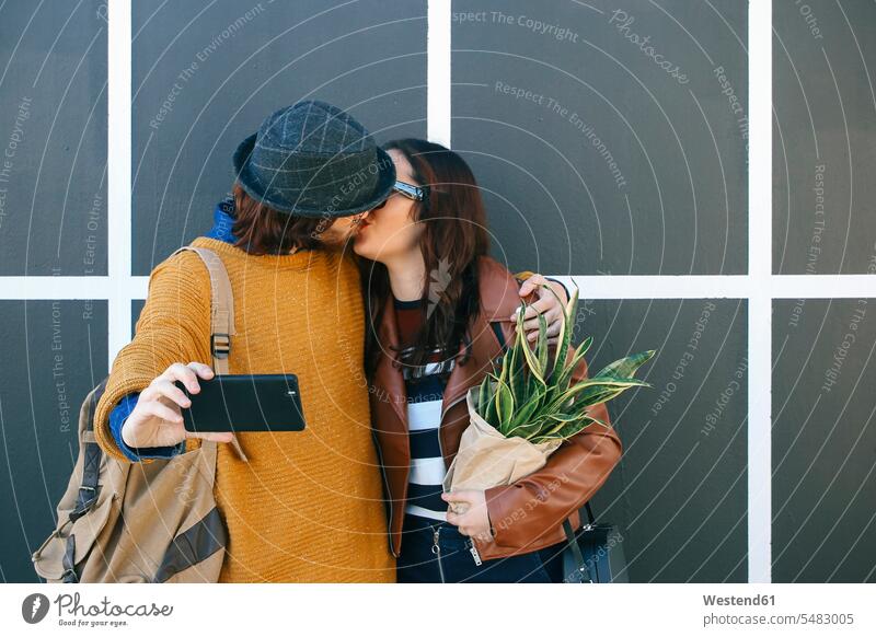 Kissing young couple taking selfie with smartphone twosomes partnership couples Smartphone iPhone Smartphones Selfie Selfies kissing kisses people persons