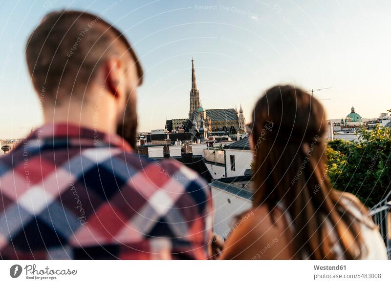 Austria, Vienna, back view of young couple on roof terrace looking at St. Stephen's Cathedral caucasian caucasian ethnicity caucasian appearance european