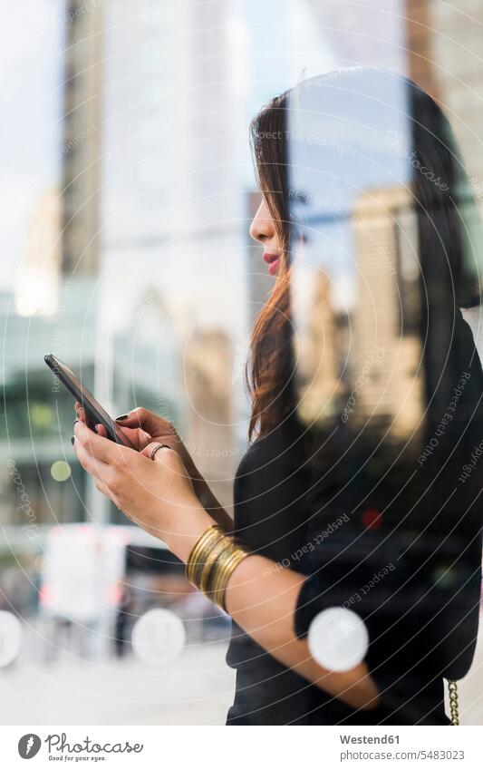 USA, New York City, Manhattan, young woman behind glass pane looking at cell phone females women Smartphone iPhone Smartphones Adults grown-ups grownups adult