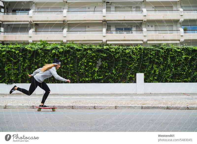 Young woman skateboarding on street female skateboarder female skater female skateboarders females women skaters people persons human being humans human beings