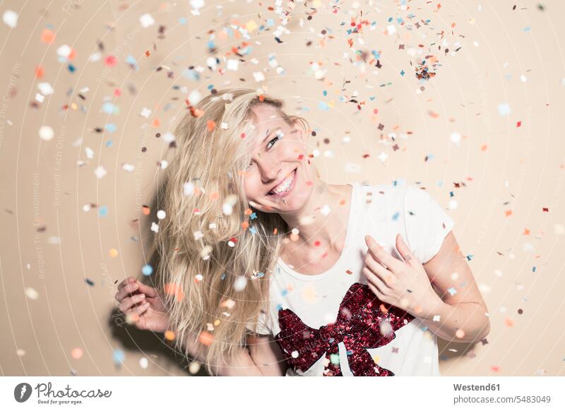 Laughing young woman with flying confetti females women portrait portraits paper Adults grown-ups grownups adult people persons human being humans human beings