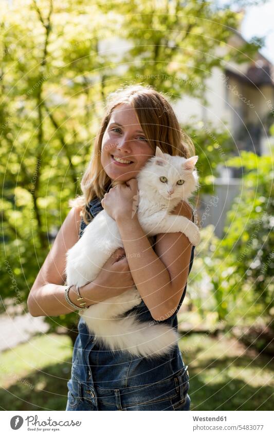 Happy woman with cat on her arms in the garden cats females women pets animal creatures animals Adults grown-ups grownups adult people persons human being