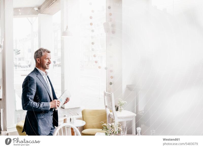 Businessman in cafe holding newspaper Business man Businessmen Business men business people businesspeople business world business life caucasian