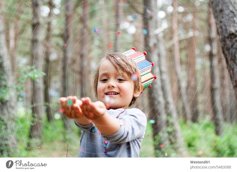 Portrait of smiling little boy wearing paper crown catching confetti Joy enjoyment pleasure Pleasant delight Children's Birthday Party