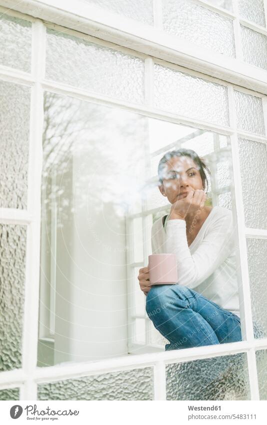 Pensive woman with cup of coffee looking out of window windows view seeing viewing females women Coffee serious earnest Seriousness austere Adults grown-ups