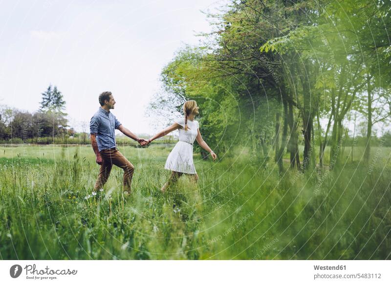 Couple in love holding hands while walking on a meadow Italy rural scene Non Urban Scene twosome togetherness love of nature in a row serial confidence