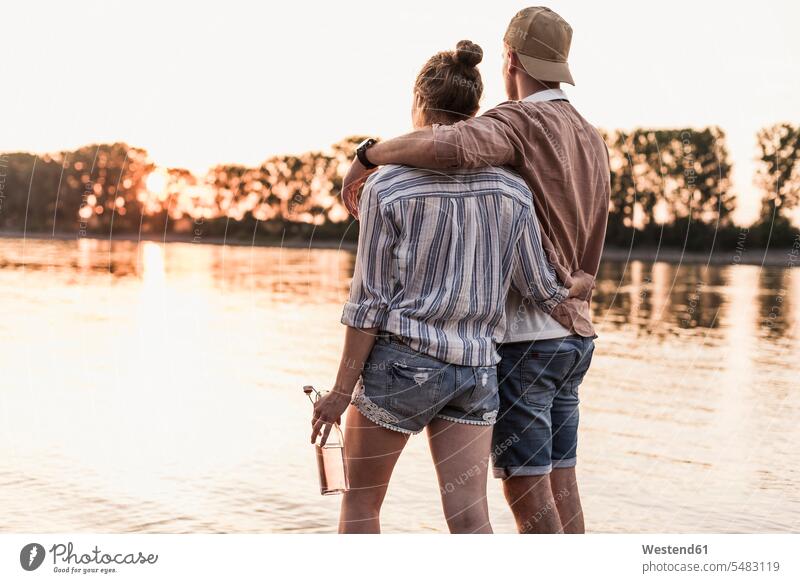 Young couple watching the sunset above a river View Vista Look-Out outlook standing sunsets sundown twosomes partnership couples atmosphere atmospheric mood