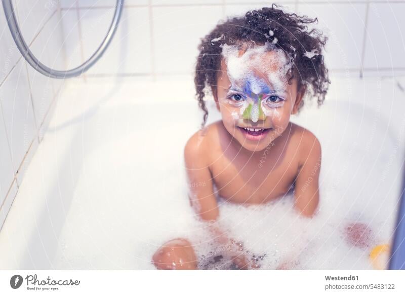 Portrait of smiling little girl with painted face sitting in a bathtub females girls bathing bathe Taking A Bath smile child children kid kids people persons