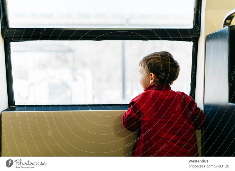 Back view of little boy on his first train ride looking through window boys males casual leisure wear casual clothing casual wear casual clothes Casual Attire